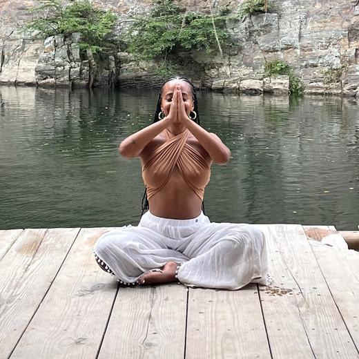 Mailu en postura de oración frente al lago